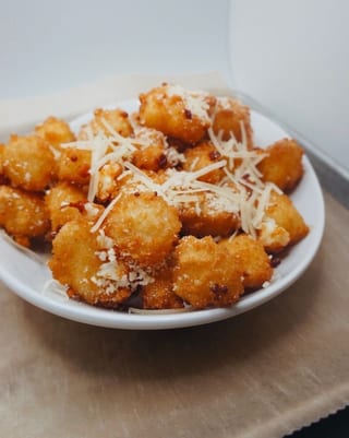 Golden fried Cheese Curds on a white plate