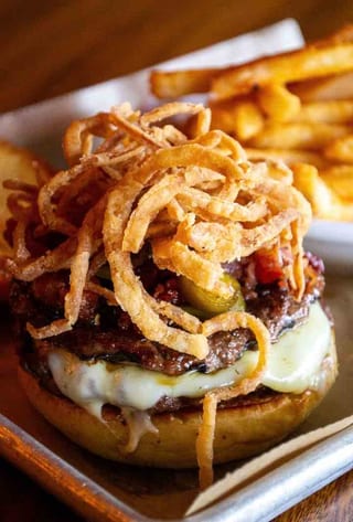 Sweet Heat burger topped with crispy onion strips, with fries